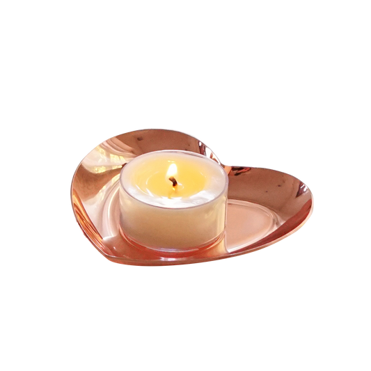 a lit tealight candle on a rose gold heart tray
