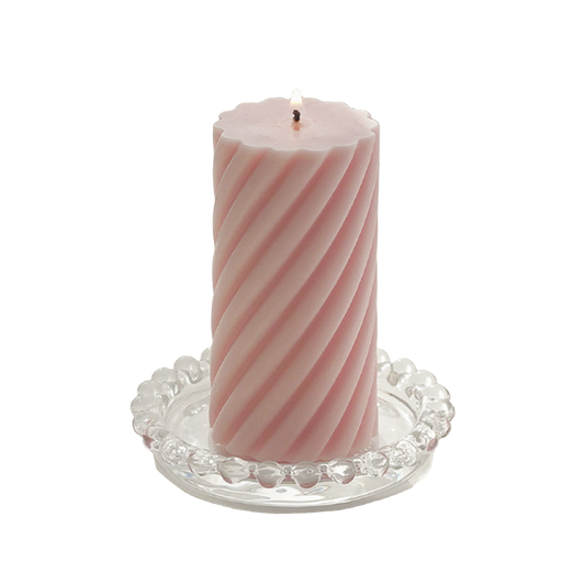 a lit blush pink sipral pillar soy candle on a clear mini beaded tray