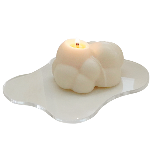 a lit cloud soy candle on a clear irregular acrylic coaster