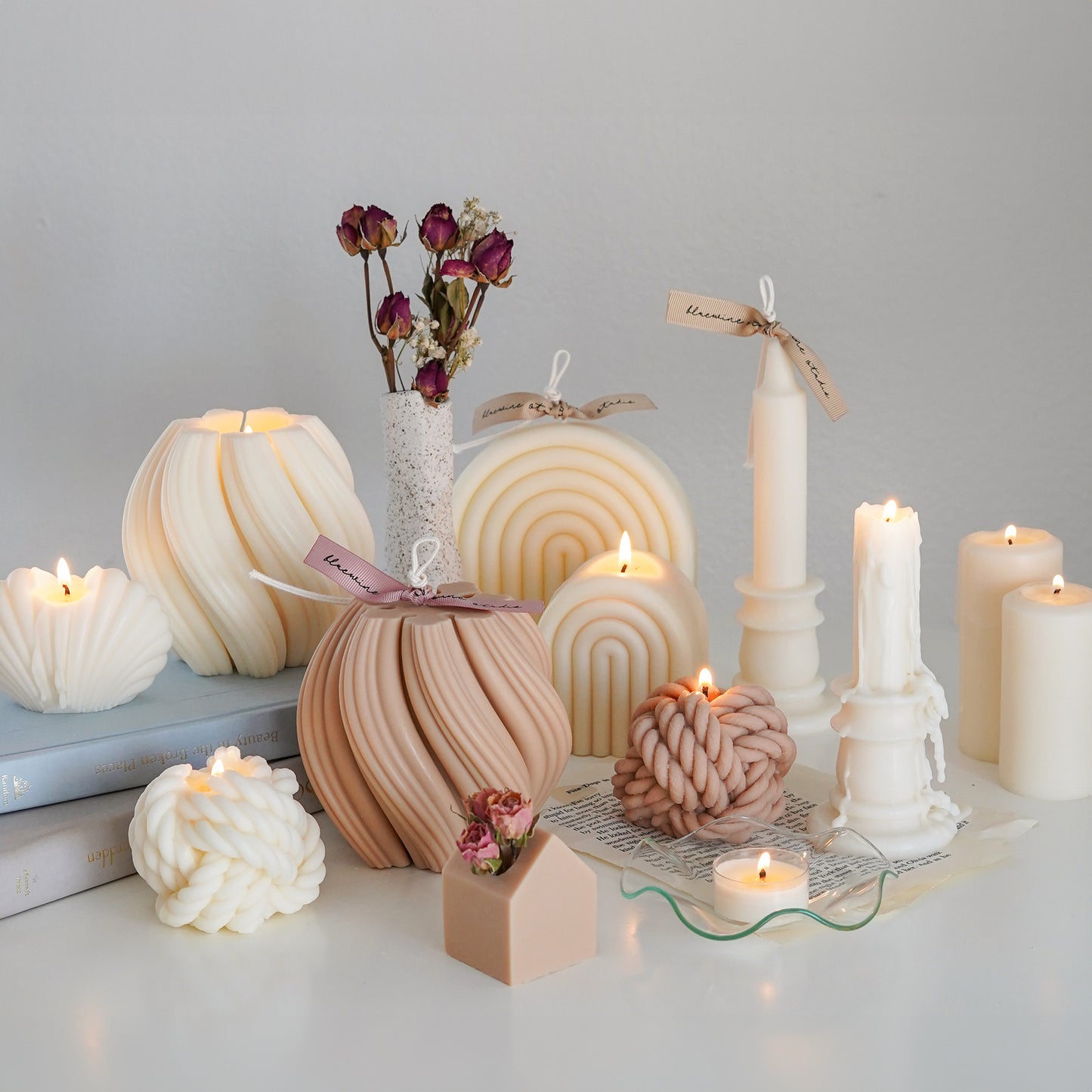 white and beige minimal sculptural soy pillar candle collections with burgundy dried flowers on the white round table