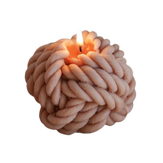 a lit beige yarn ball shape soy pillar candle