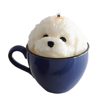 a lit white bichon soy candle placed in a blue mug