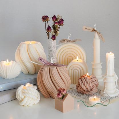 minimal white and beige sculptural soy pillar candle collection with books and rose dried flowers on white round table