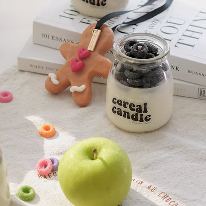 a lit colorful cereal candle, fruit loops wax melts, a green apple, oreo candle, gingerbread scented wax, 101 Essays that will change the way you think by Brianna Wiest placed on kitchen cotton fabric