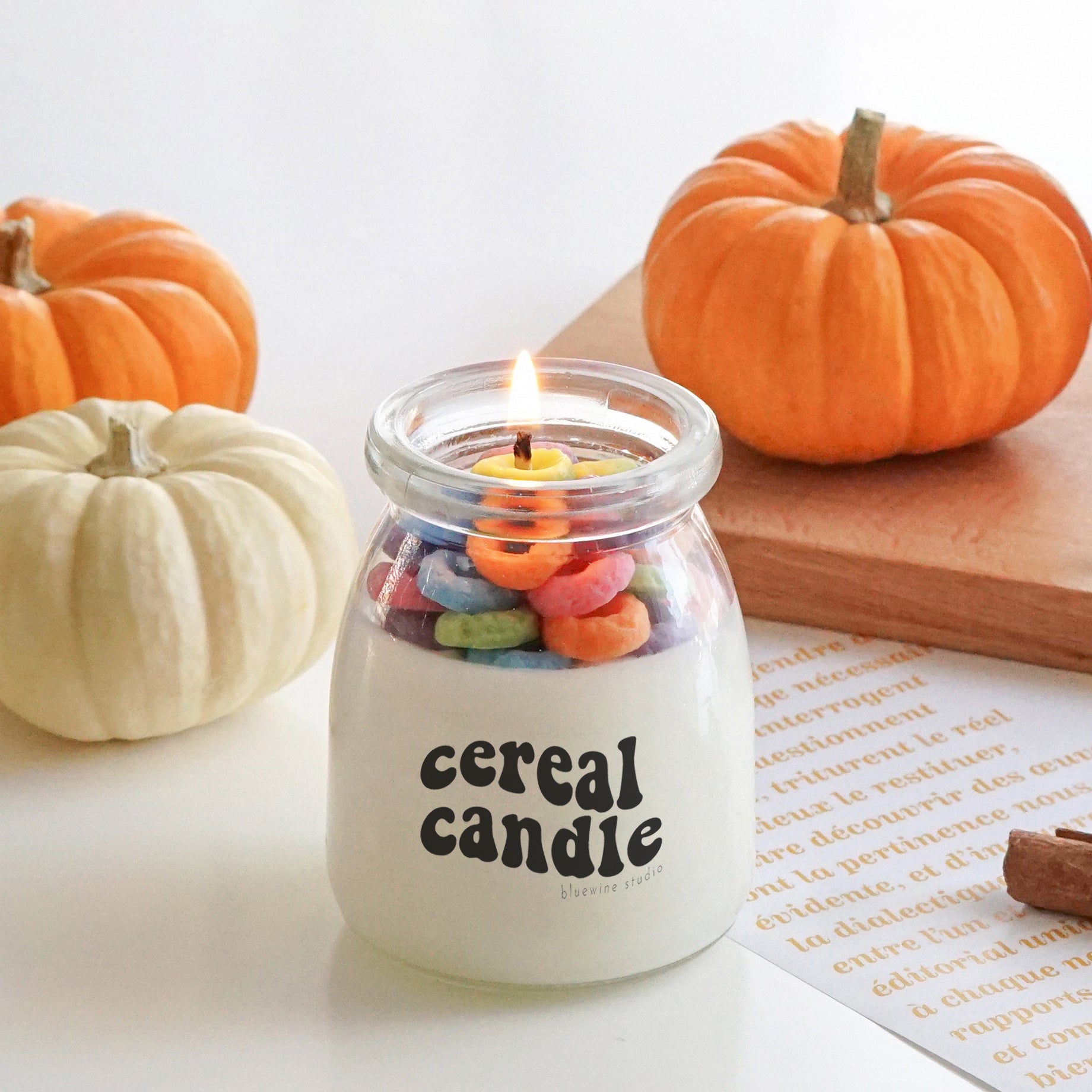 a lit fruit loops cereal candle filled with colorful cereal wax melts, cinnamon sticks, white and orange pumpkins, Ikea mini wood cutting board