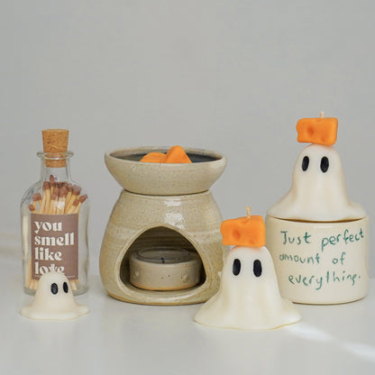 ghost candles with cheese on top, cheese wax melts, wax warmer, mug, and match bottle on a vanity table