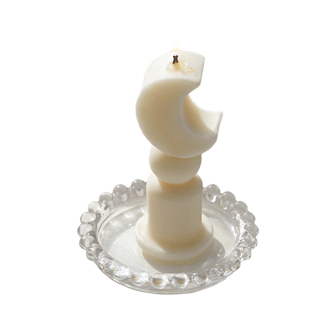 a lit dreamy aesthetic crescent moon shaped soy pillar candle on a clear beaded round tray