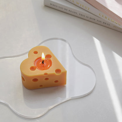 a lit heart shape cheese candle on a clear irregular acrylic coaster