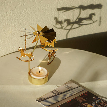 merry-go-round gold tealight candle holder with a lit tealight candle and postcards on white end table