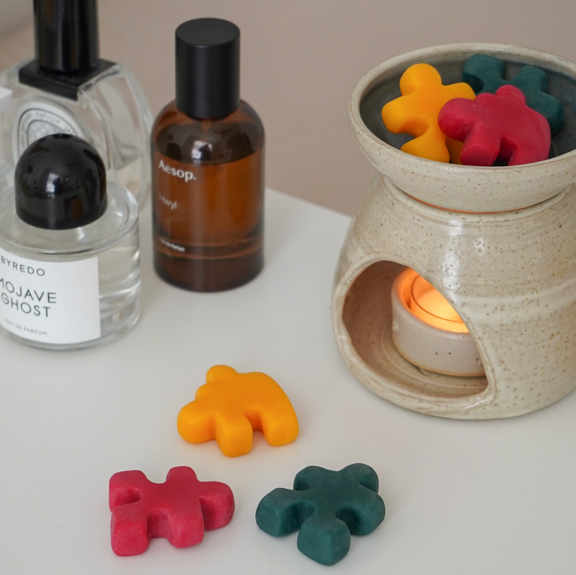 ed, yellow, and green puzzle shape wax melts in a wax warmer and fragrances on the white table