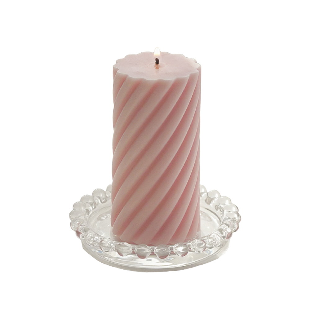 a lit blush pink sipral pillar soy candle on a clear mini beaded tray