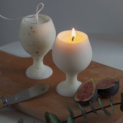 fig slices, eucalyptus leaves, cheese knife, and a dotted pattern white soy pillar wine candle, and a lit white wine candle on ikea mini wood board